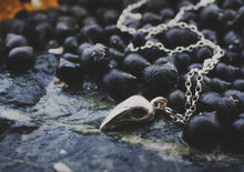 silver skull pendant on berries