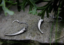 silver claw earrings displayed on a rock