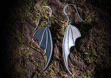 bat wing silver earrings on a moss covered tree bark