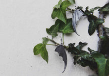 bat wing silver earrings hanging on ivy