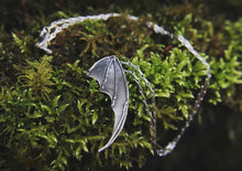 bat wing silver pendant on a moss background