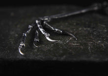 silver blackbird claw on a dark metal surface